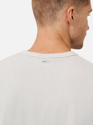 A man is seen from behind wearing an Industrie The Del Sur Tee in light beige. The 100% cotton shirt has a small "Industrie" tag on the upper back, with his neck and head visible above the T-shirt.