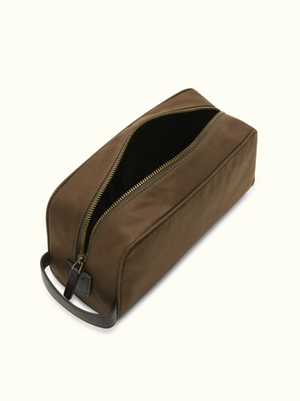The RM Williams Hawkesbury Washbag is a brown, rectangular waxed cotton travel bag with a wide, partially open zipper showing its dark waterproof lining. It has a small handle on one end and is set against a plain light background.