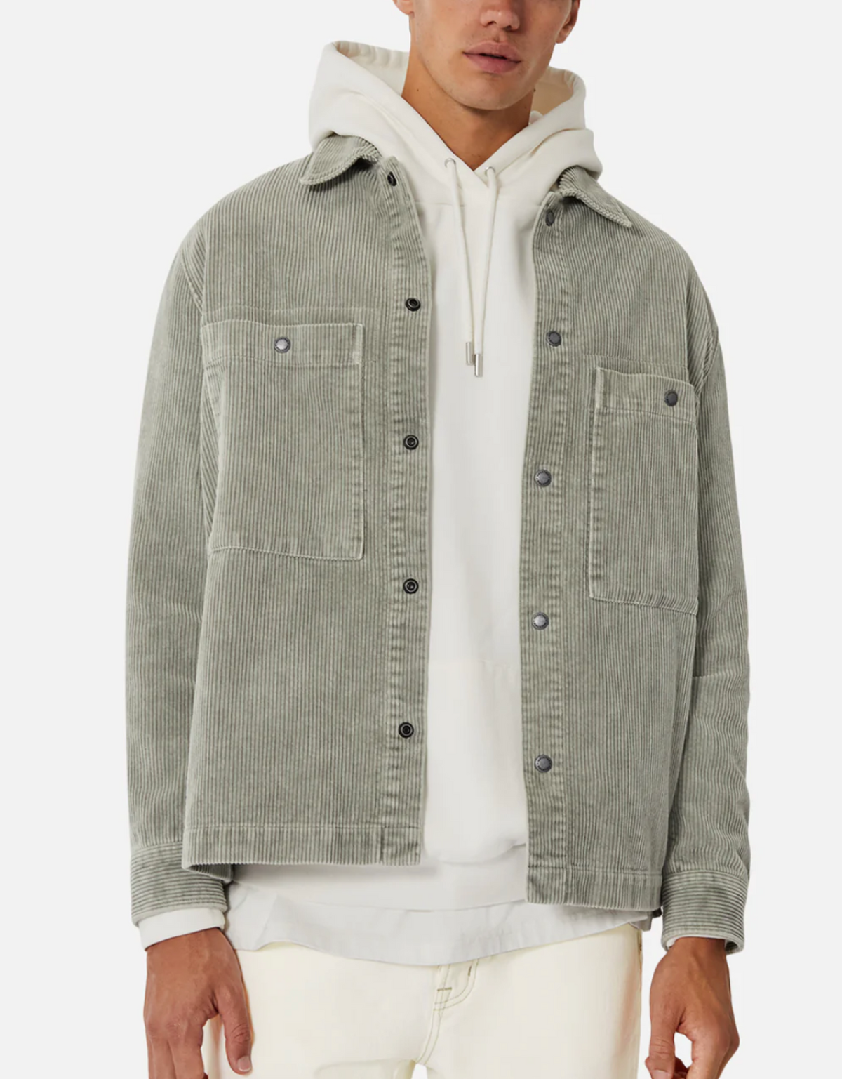 A person wears the Industrie The Atmore Jacket in light gray with corduroy details over a white hoodie and off-white pants, standing against a plain white background.