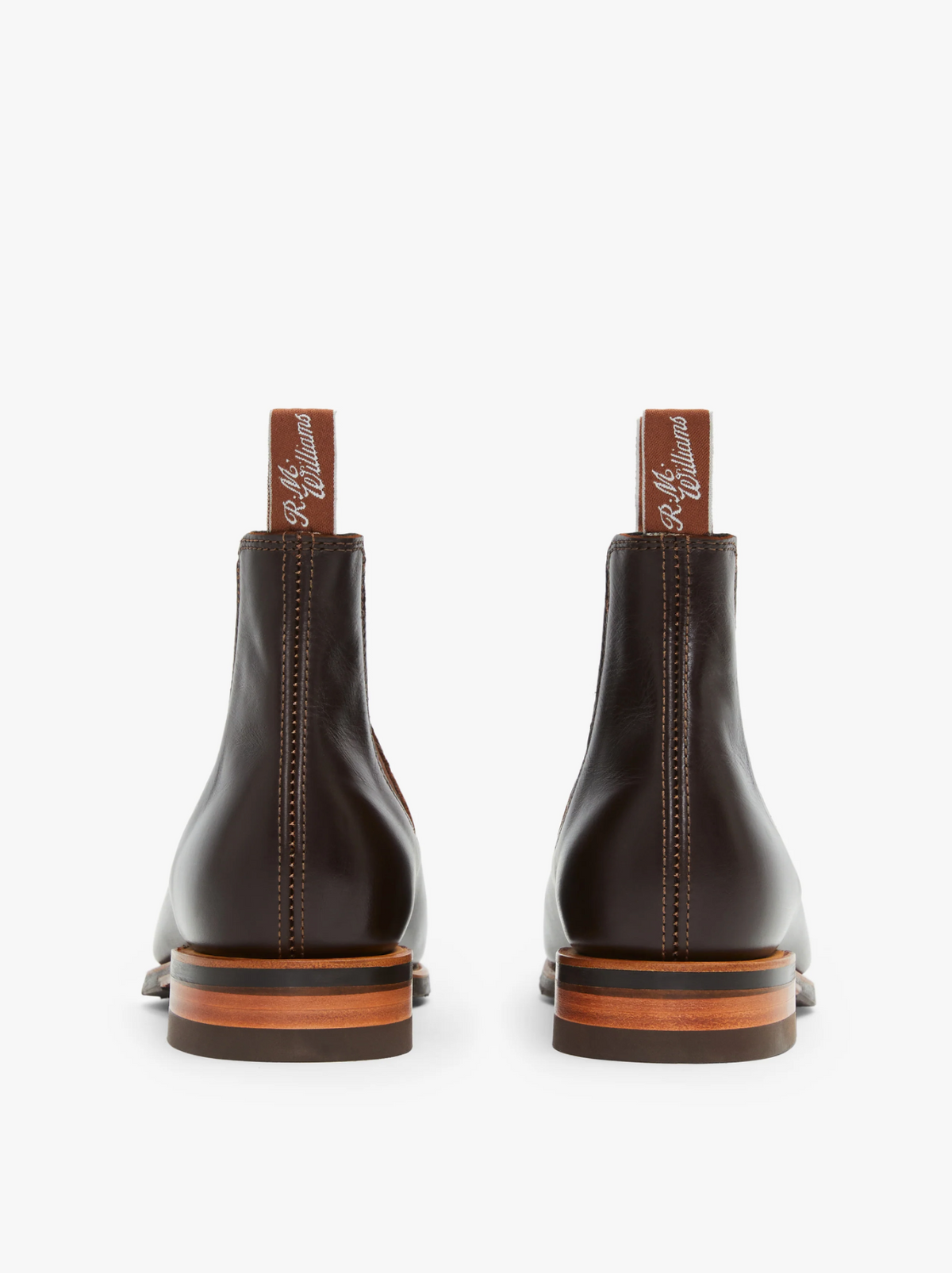 Introducing the RM Williams Dynamic Flex Craftsman Boot: A polished, dark brown yearling leather Chelsea boot featuring elastic side panels and tan pull tabs accented with stitched brand names. These boots showcase a sleek design with a wooden-look sole and a slight heel for added sophistication.