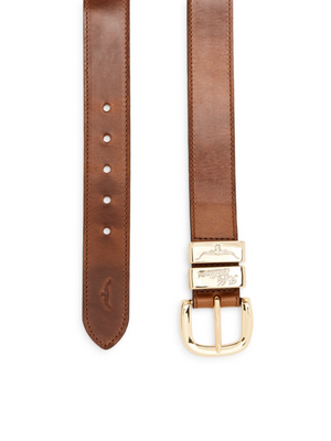 Close-up of an RM Williams Drover Belt, crafted in Australia from brown pull-up leather. It features a polished finish and a gold buckle with intricate engravings and five adjustment holes, all in a plain design.
.