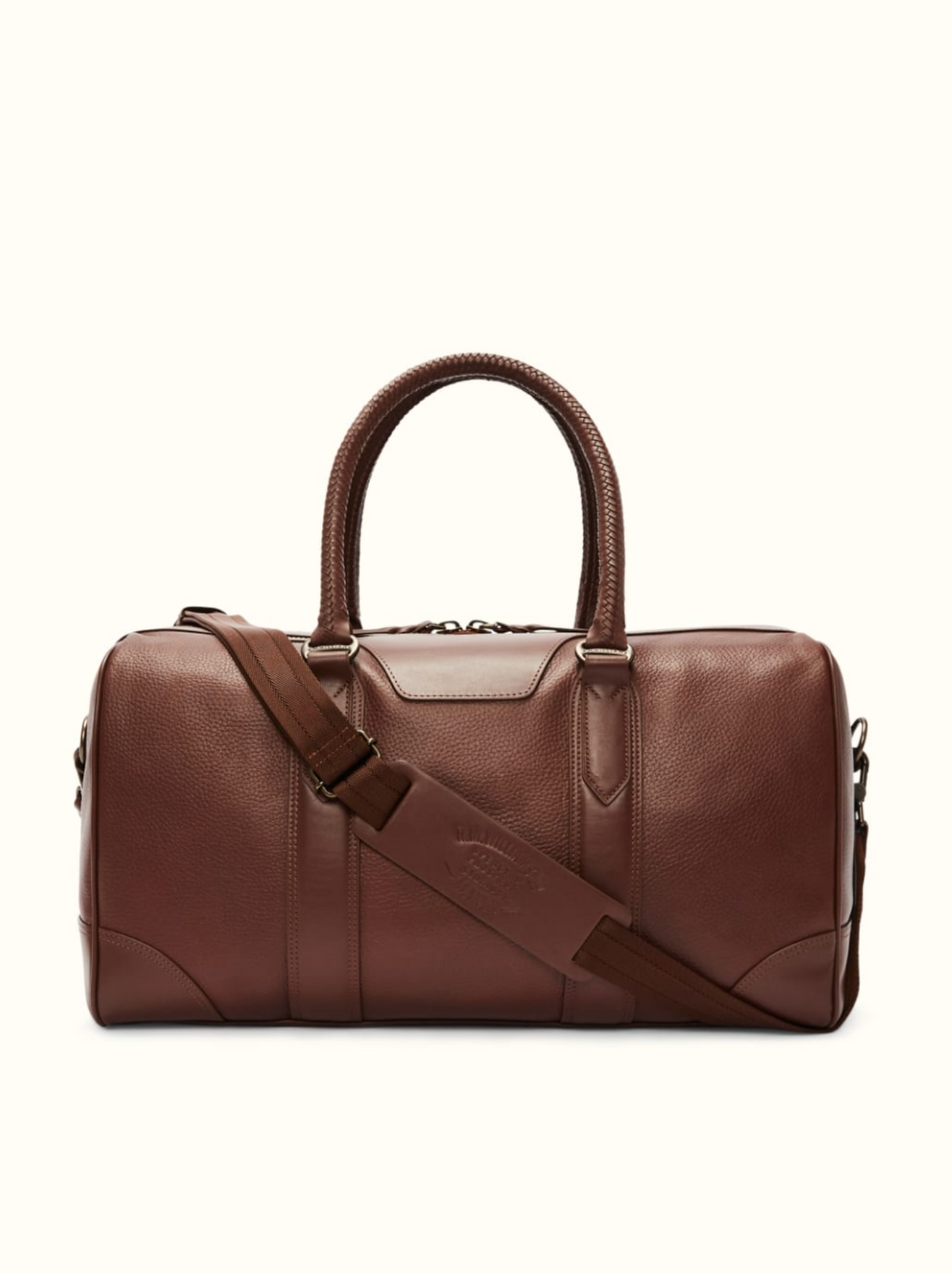 The RM Williams Overnight Bag is a sleek brown full grain leather duffle with sturdy handles, a detachable shoulder strap, and subtle stitching. Featuring a top zipper closure, this stylish bag is perfect for transporting all your travel essentials effortlessly.