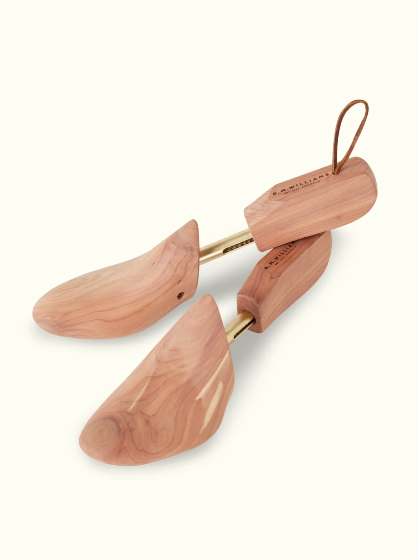 Introducing the RM Williams Red Cedar Boot Tree, a premium leather care product crafted with brass rods and leather loops. These cedar shoe trees preserve shape and absorb moisture while showcasing natural grain patterns and rich brown shades.