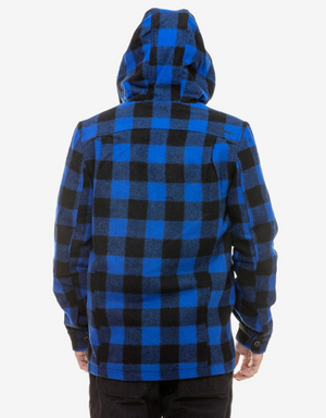 A person wearing a Swanndri Hudson Hoody, featuring a large blue and black check pattern and long sleeves with buttoned cuffs, stands facing away from the camera. The New Zealand wool hoody is contrasted against a plain white background, with the person's hands resting by their sides.