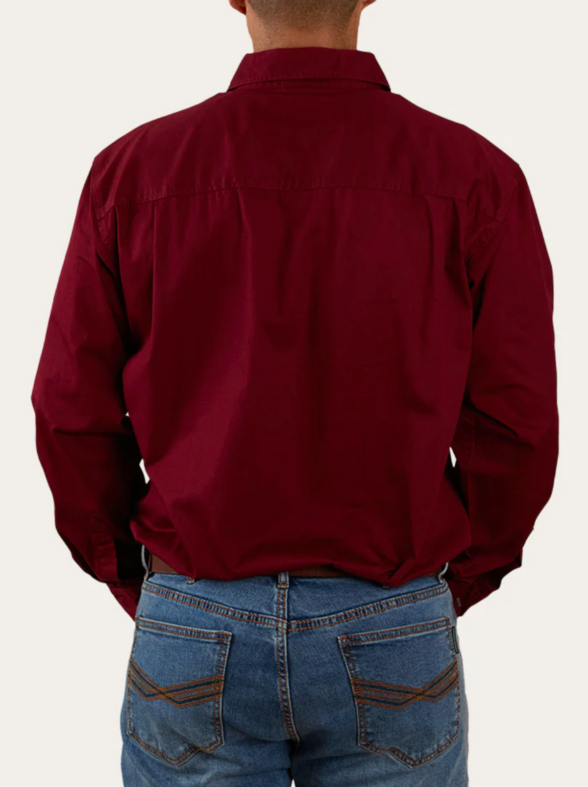 A person is seen from the back, wearing a Ringers Western King River Half Button Shirt in maroon and blue jeans against a plain light background. The shirt is made from 100% cotton for comfort and durability.