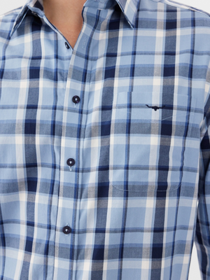 A close-up shows a person wearing the RM Williams Collins Shirt in blue and white plaid. The lightweight cotton twill fabric includes front buttons, a chest pocket, and adjustable cuffs, featuring shades of light and dark blue with crisp white stripes.