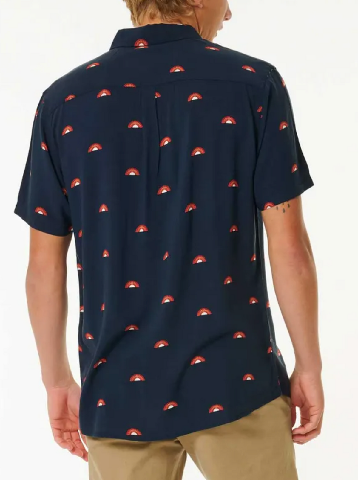 A person is seen from the back against a white background, wearing the Rip Curl Party Pack Short Sleeve Shirt in navy blue with a red and white pattern and tan pants, highlighting its stylish look and comfortable fit.