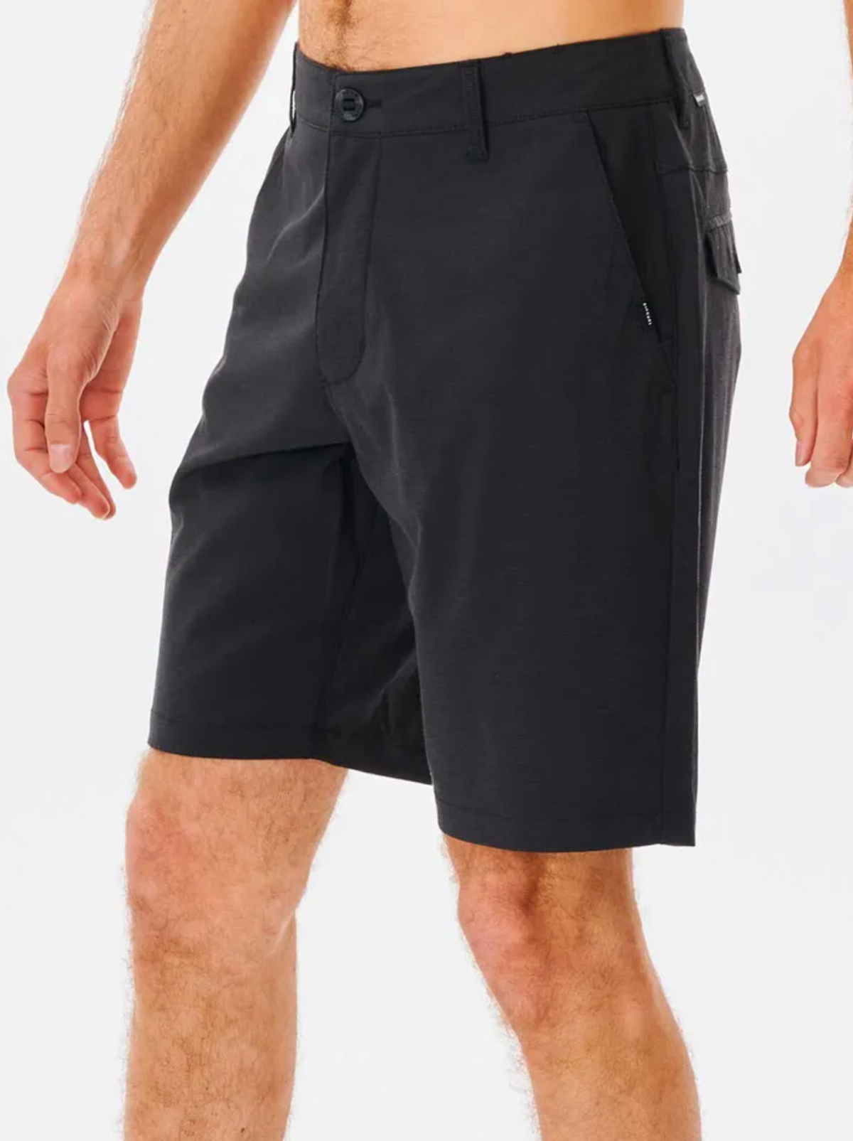 A person wears black Rip Curl Boardwalk Phase Nineteen Shorts with front pockets and a button closure, shown from mid-torso to knees against a white background.