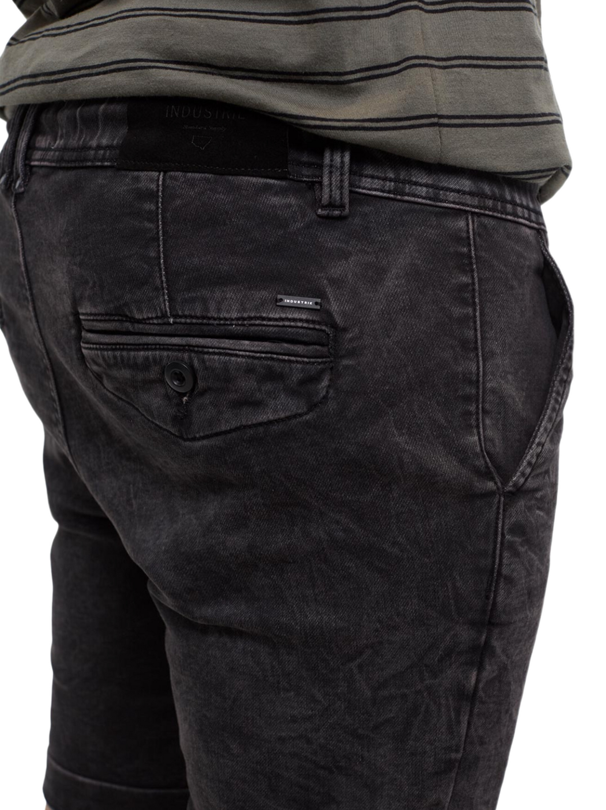 Close-up of a person wearing the Industrie The Drifter Denim Short in faded black, featuring a buttoned back pocket, paired with a striped green and gray shirt—ideal for relaxed summer style.