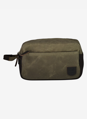 The Swanndri Island Bay Wash Bag is made from green cotton wax canvas, featuring a front pocket, black side panel, small handle, and leather logo patch for a stylish yet functional design.