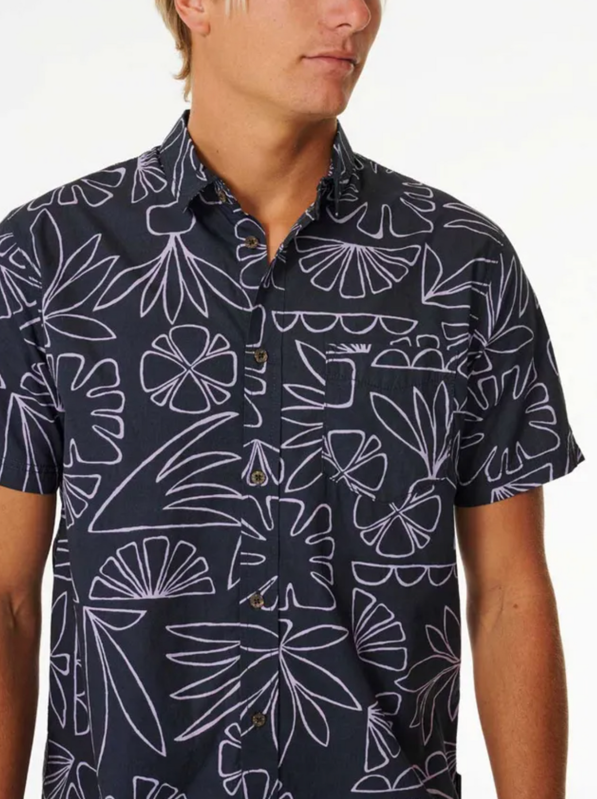 A person wearing the Rip Curl SWC Short Sleeve Shirt in navy blue with a white abstract floral and leaf pattern. The upper torso and part of the face are visible against a plain background.