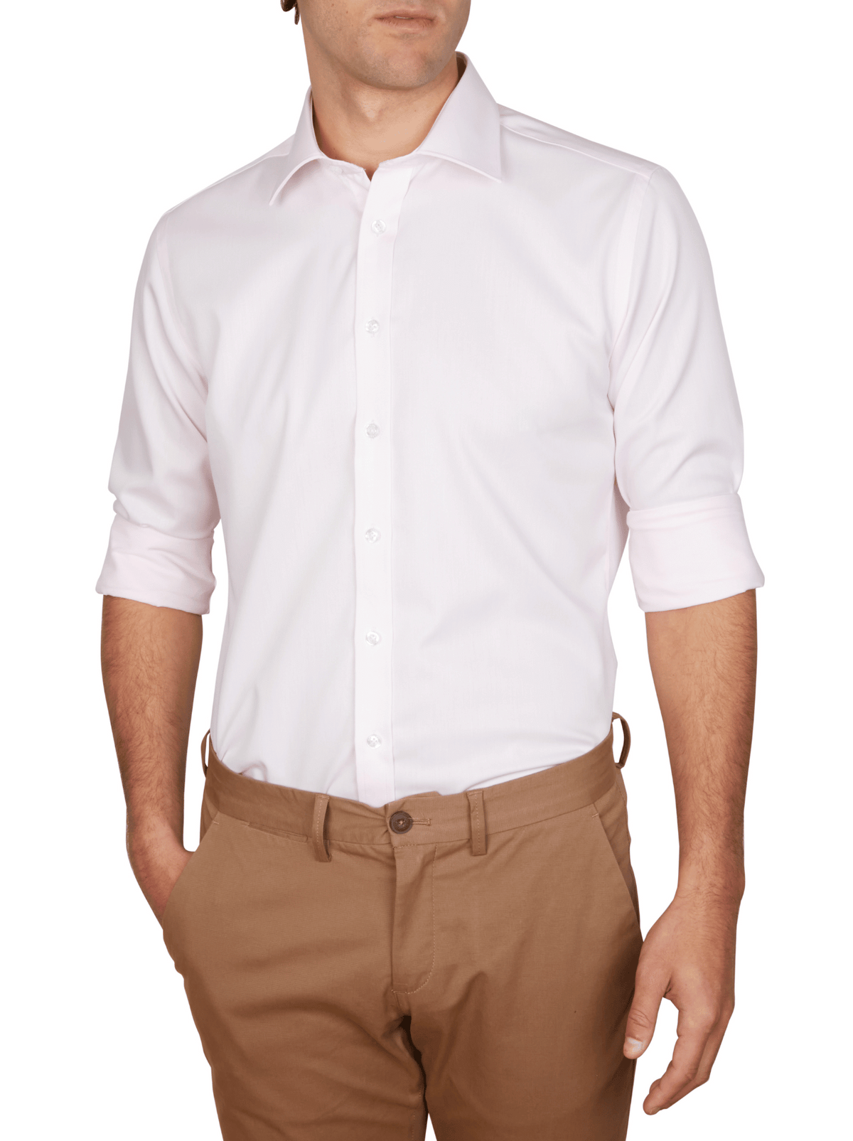 A man is shown from shoulders to thighs, wearing an Abelard Non Iron Cotton Twill Slim Fit Shirt in light pink with rolled-up sleeves and tan pants, standing with his hands in his pockets.