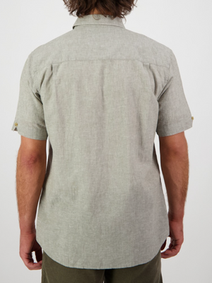 The image shows a person from the back in a Swanndri Lowell v2 Short Sleeve Shirt, light gray with a straight hem and collar, featuring an embroidered swan logo. They have brown hair against a plain white background.