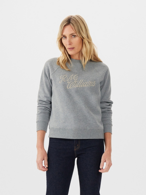 A person with long blonde hair is wearing the RM Williams R.M.W Womens Script Crew in gray. Complementing the classic look, they're also in dark jeans, standing against a plain white background.