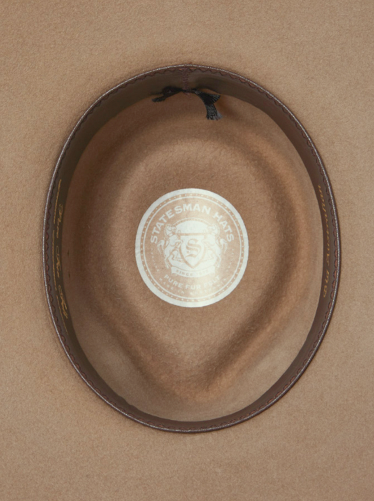 Inside view of the Statesman Big Australian Fur Felt Hat with a leather band features a central sticker with an emblem and the text "STATESMAN HATS" and "FINE FUR," showcasing the superior rabbit fur felt craftsmanship.