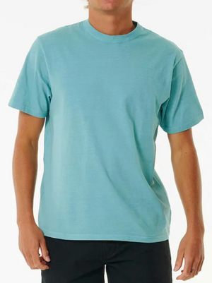 A person wears a light blue Rip Curl Plain Wash Tee and black pants against a white backdrop. The T-shirt boasts a simple, casual style with short sleeves and offers a relaxed fit, ideal for daily wear.