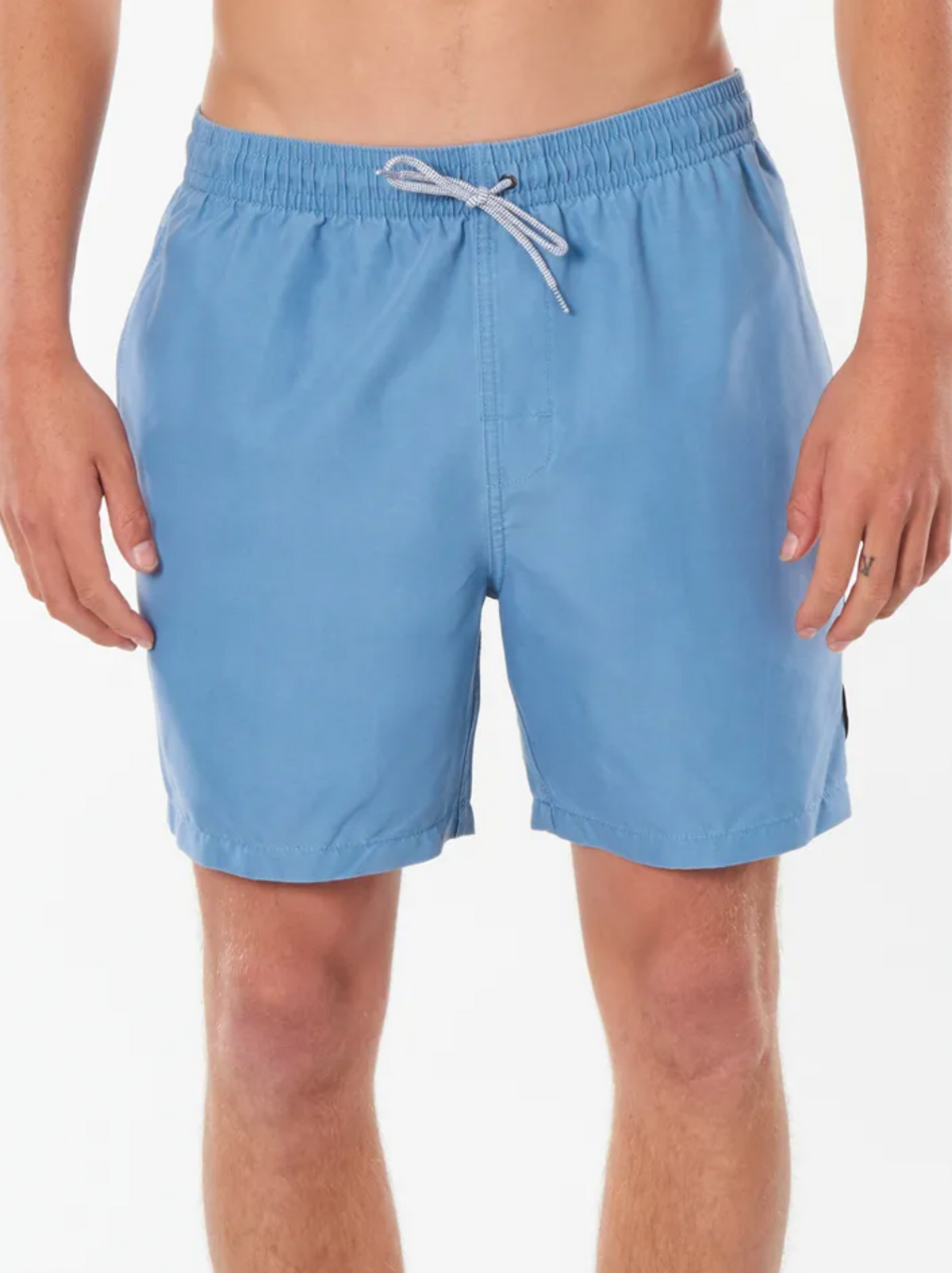 Someone is wearing light blue Rip Curl Bondi Volley trunks, featuring an elastic waistband and drawstring. These knee-length swim trunks are ideal for a beach outing, set against a plain white background.