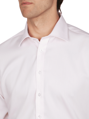A man wears the Abelard Non Iron Cotton Twill Slim Fit Shirt in light pink with a pointed collar, showing his upper torso and part of his face against a neutral white background.
