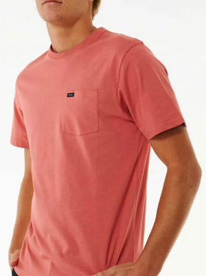 Person wearing a classic staple: a salmon-colored Rip Curl Plain Pocket Tee with short sleeves and a small black tag on the chest pocket, set against a plain white background.