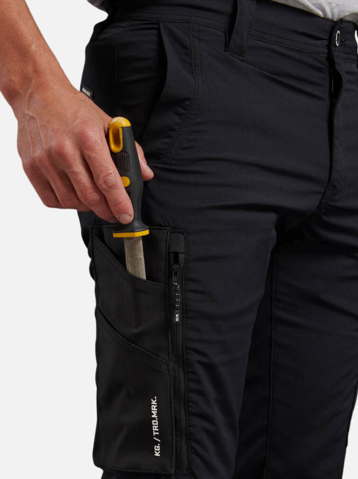 A person puts a yellow and black-handled screwdriver into the zippered side pocket of King Gee Trademark Cargo Pant.