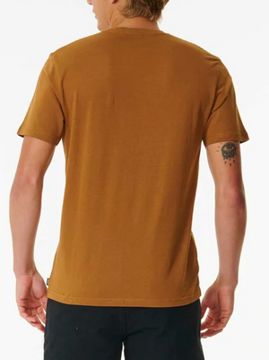 A light-skinned person with short light brown hair is seen from behind, wearing a mustard brown Rip Curl Brand Icon Tee and dark pants. They have a tattoo of a dripping eye on their upper left arm.
