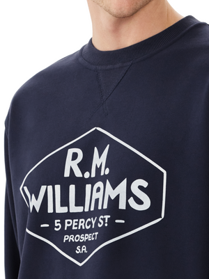 Wearing the RM Williams Gladstone Crew Neck in navy, made from soft cotton fleece with a white graphic displaying "5 Percy St, Prospect, S.A.," one enjoys a comfortable relaxed fit and timeless design.