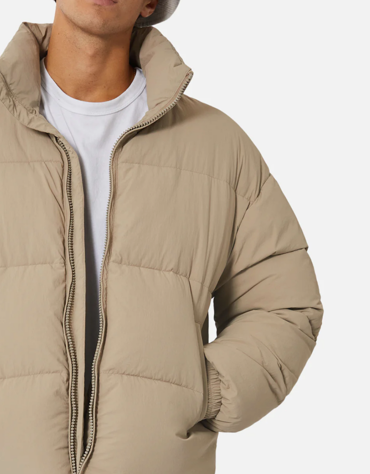 A person is wearing the Industrie The Regent Puffer Jacket in beige with quilted padding over a white t-shirt. The unzipped jacket, showcasing its Industrie label, exposes the person from the shoulders down against a plain white background.