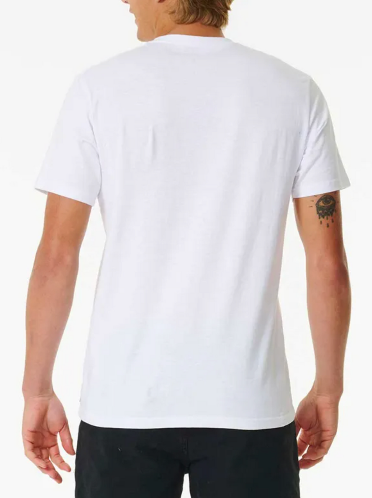 A person with medium-length hair is seen from behind, wearing a Rip Curl Brand Icon Tee in plain white with black pants. Made of 100% cotton for comfort, the tee contrasts with their small right-arm tattoo against its plain background.
