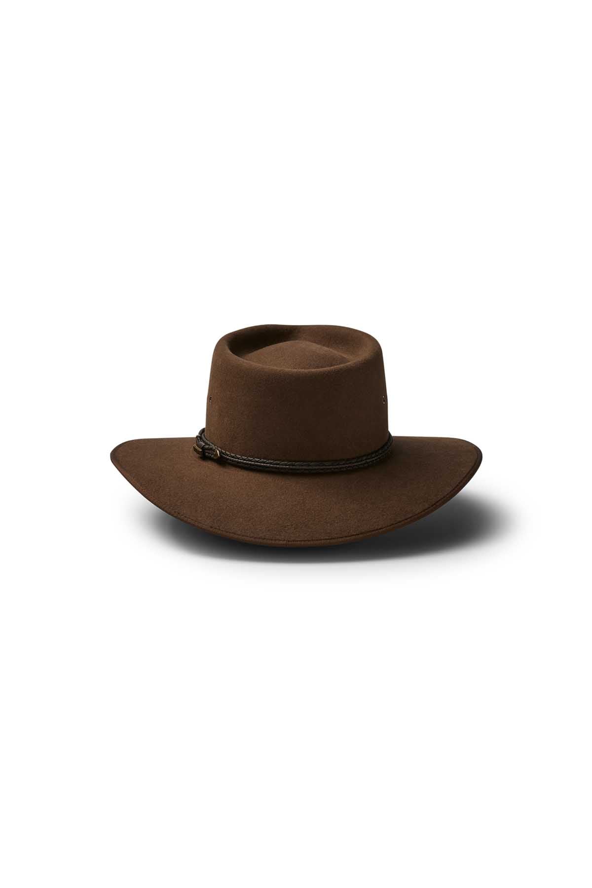 The Akubra Cattleman is a brown wide-brimmed hat with a flat crown and thin dark braided band, ideal for outdoor adventurers seeking rugged style. Shown against a white background.
