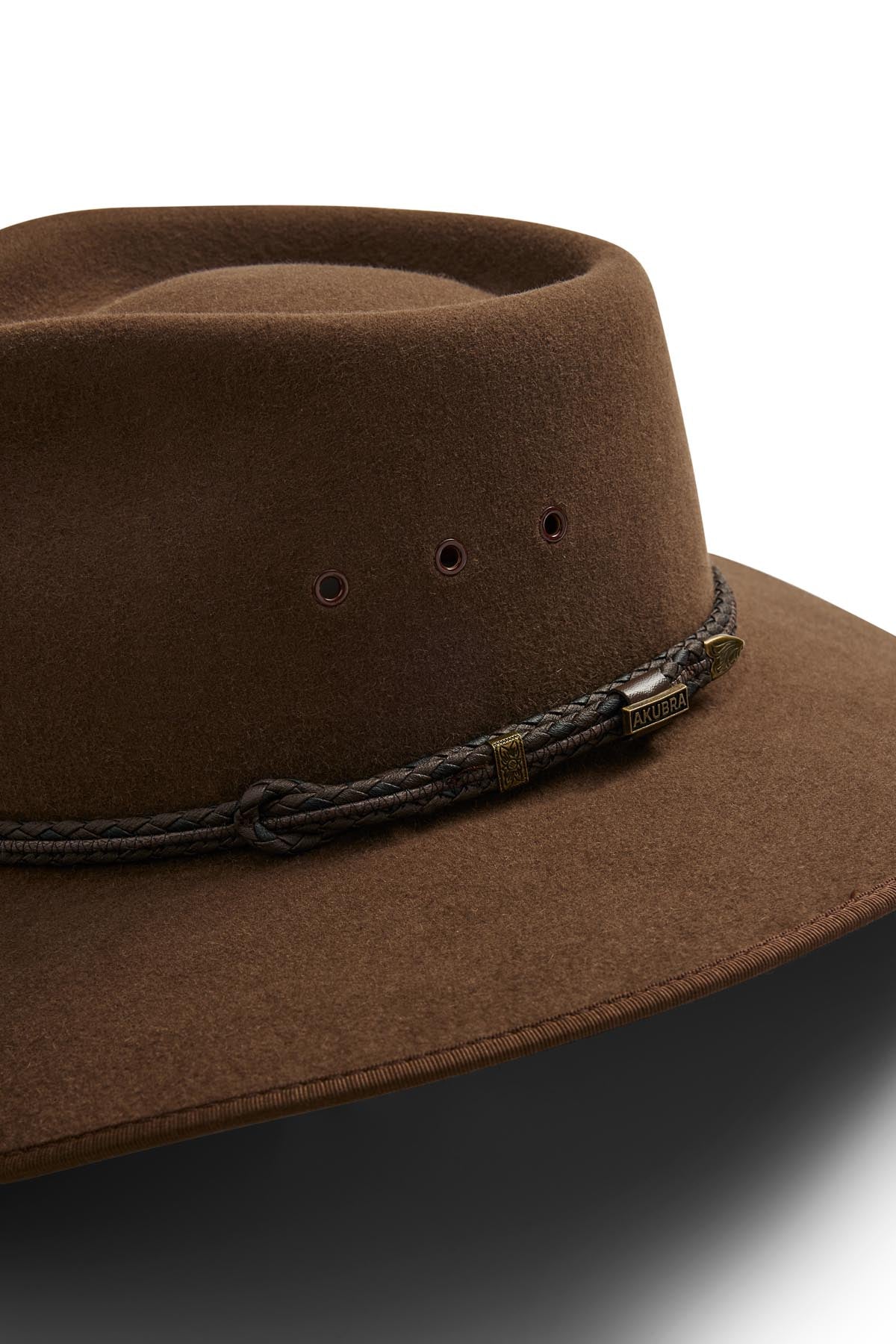 The Akubra Cattleman is a brown felt hat with a wide brim, braided dark brown band, and small ventilation holes above the band—combining rugged style with practicality for outdoor adventurers.