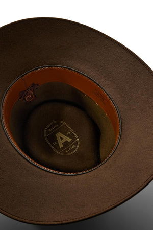 A close-up of the Akubra Cattleman reveals its brown felt interior with a leather sweatband, fine stitching, and a stamped logo featuring “A,” “MASTER,” and “67”—a durable hat ideal for outdoor enthusiasts.