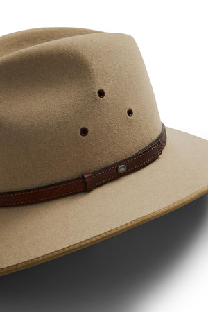 A close-up of the Akubra Coober Pedy tan felt hat features ventilation holes and a brown leather band, photographed on a white background—a true icon of Australian lifestyle.