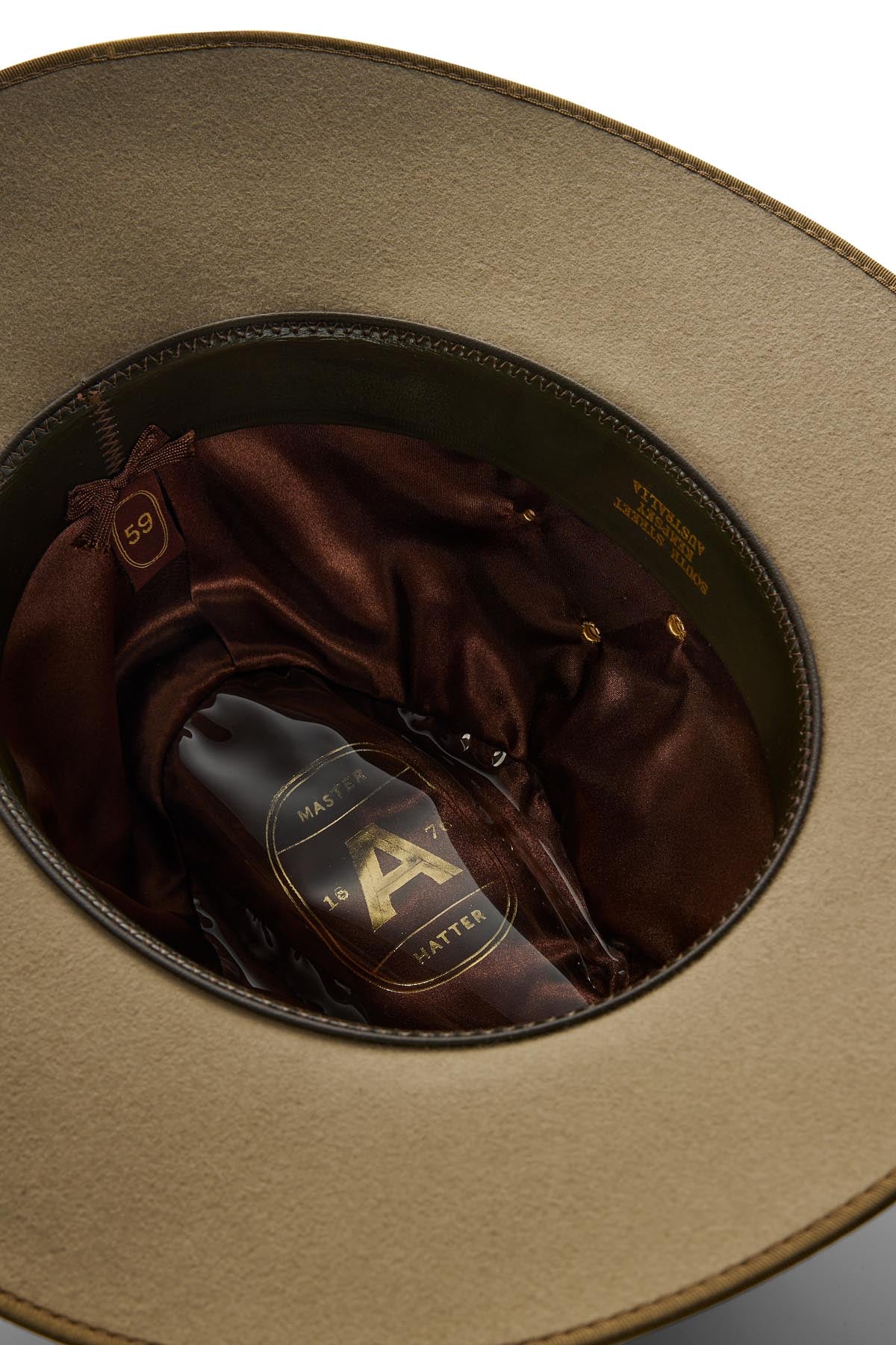 A close-up of the Akubra Coober Pedy hat’s beige felt interior shows a brown satin lining, a “Master Hatter” label with a large "A", and size 59—ideal for life in Australia.