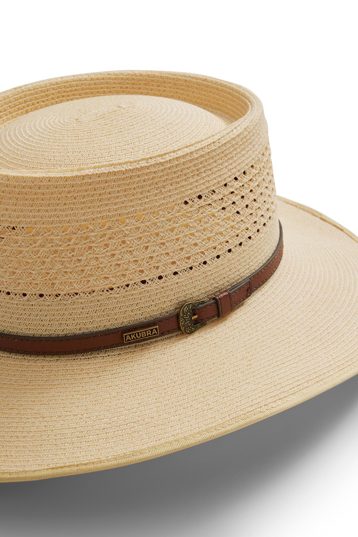 A close-up of the Akubra Byron Straw Hat—a light tan straw summer hat with a wide brim, woven detailing, and a brown leather band featuring a small gold Akubra badge.