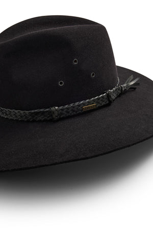 The Akubra Riverina is a black, wide-brimmed felt hat with a braided band, metallic tag, and two ventilation eyelets for sun protection. Its broad brim and crown stand out clearly against a white background.