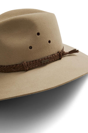 The Akubra Riverina is a tan wide-brimmed felt hat with a braided brown leather band, ventilation holes, and a soft leather sweatband for comfort and sun protection, finished with a small metal Akubra Riverina tag.