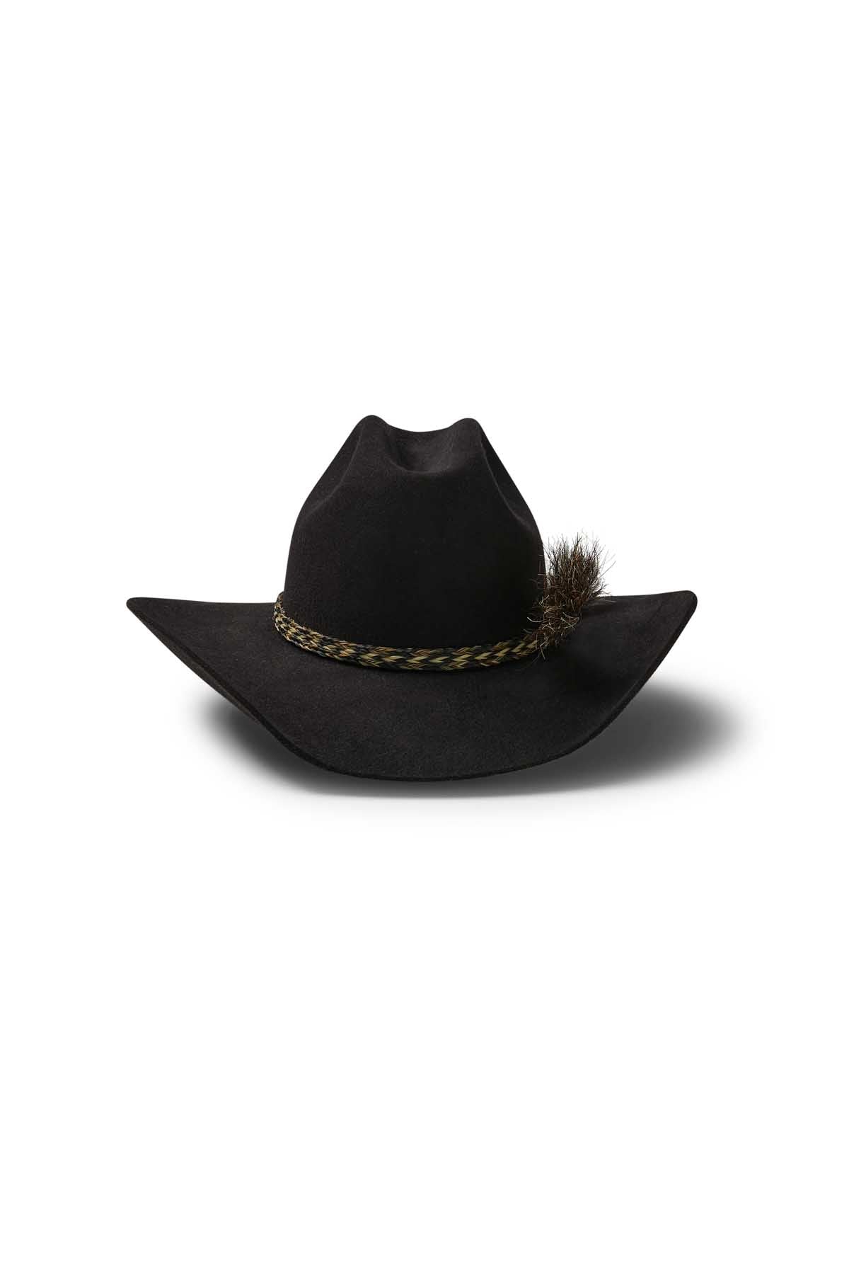 The Akubra Rough Rider is a black wide-brim hat with a Cattleman crown, braided band, and decorative feather on one side, shown against a white background.