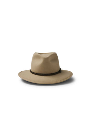 The Akubra Traveller is a tan fedora hat featuring a wide brim, dark braided band, and classic felt design, shown against a white background.
