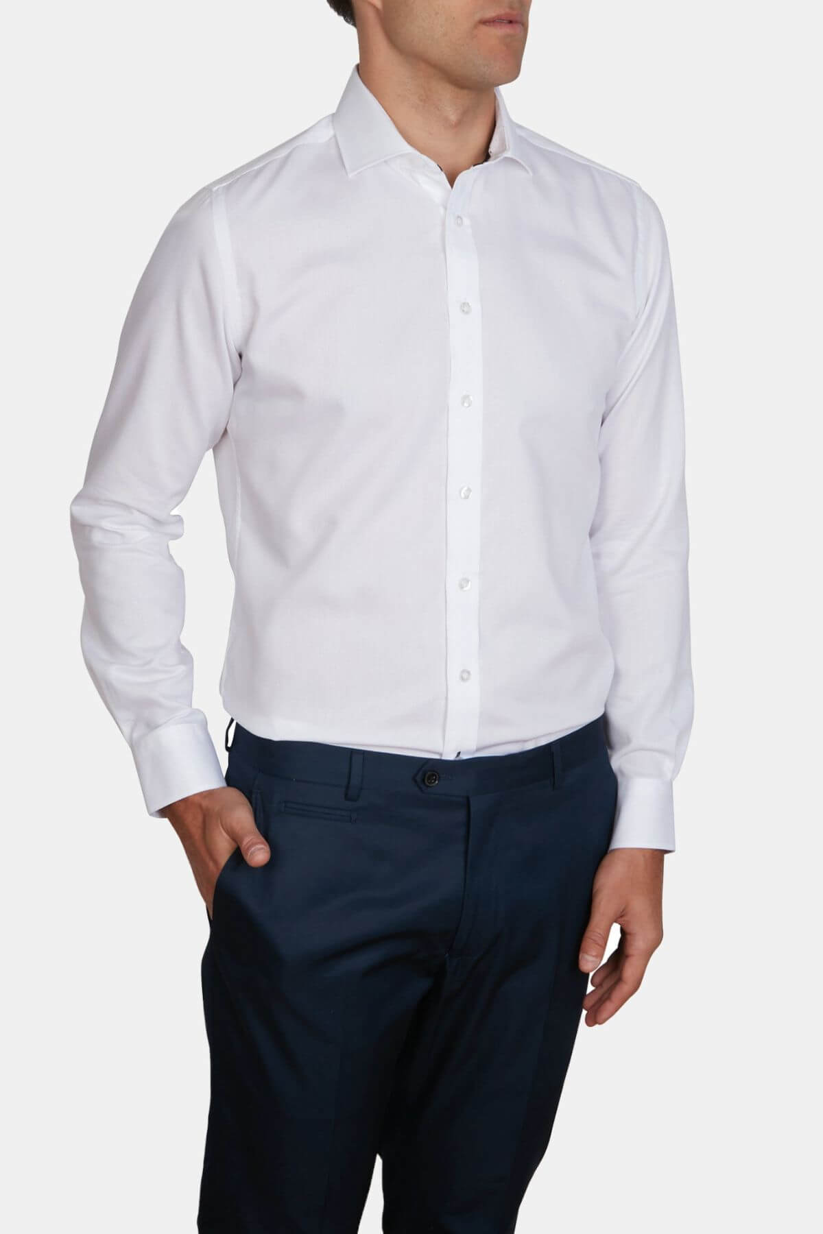 A man wearing the Abelard Bedford Dobby Slim Fit Shirt with a cardinal cut away collar and dark navy dress pants, standing against a plain white background with one hand in his pocket.