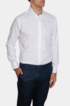 A man wearing the Abelard Bedford Dobby Slim Fit Shirt with a cardinal cut away collar and dark navy dress pants, standing against a plain white background with one hand in his pocket.