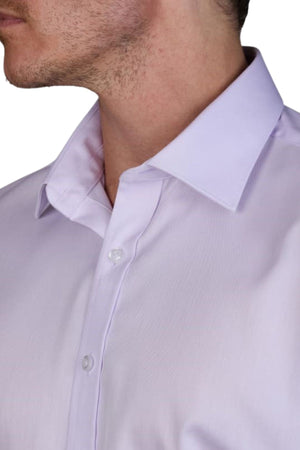 Close-up of a man in the Abelard Non Iron Cotton Twill Slim Fit Shirt, light lavender with a pointed collar. The shirt is buttoned up to show two white buttons, and the image highlights part of his clean-shaven face and neck stubble.
