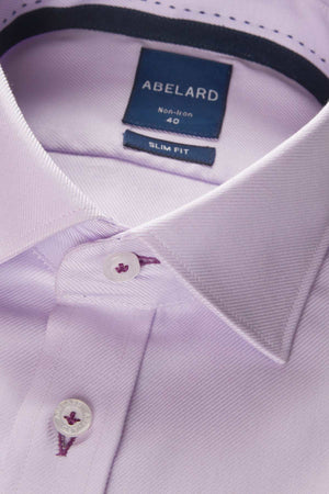 Close-up of the Abelard Non Iron Cotton Twill Slim Fit Shirt in light purple, showcasing its cutaway collar and a visible label reading "ABELARD, Non-Iron, 40." The shirt features white buttons with contrasting purple stitching on the buttonholes. The crisp texture and fine details of the non-iron cotton twill fabric are evident.