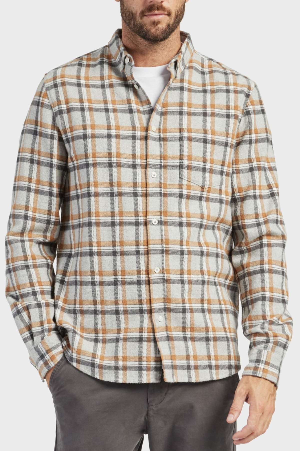 A man wears the Academy Brand Boston Shirt, a 100% cotton yarn-dye mid-weight check shirt, layered over a white t-shirt. He stands against a plain background with his left hand in his pocket.