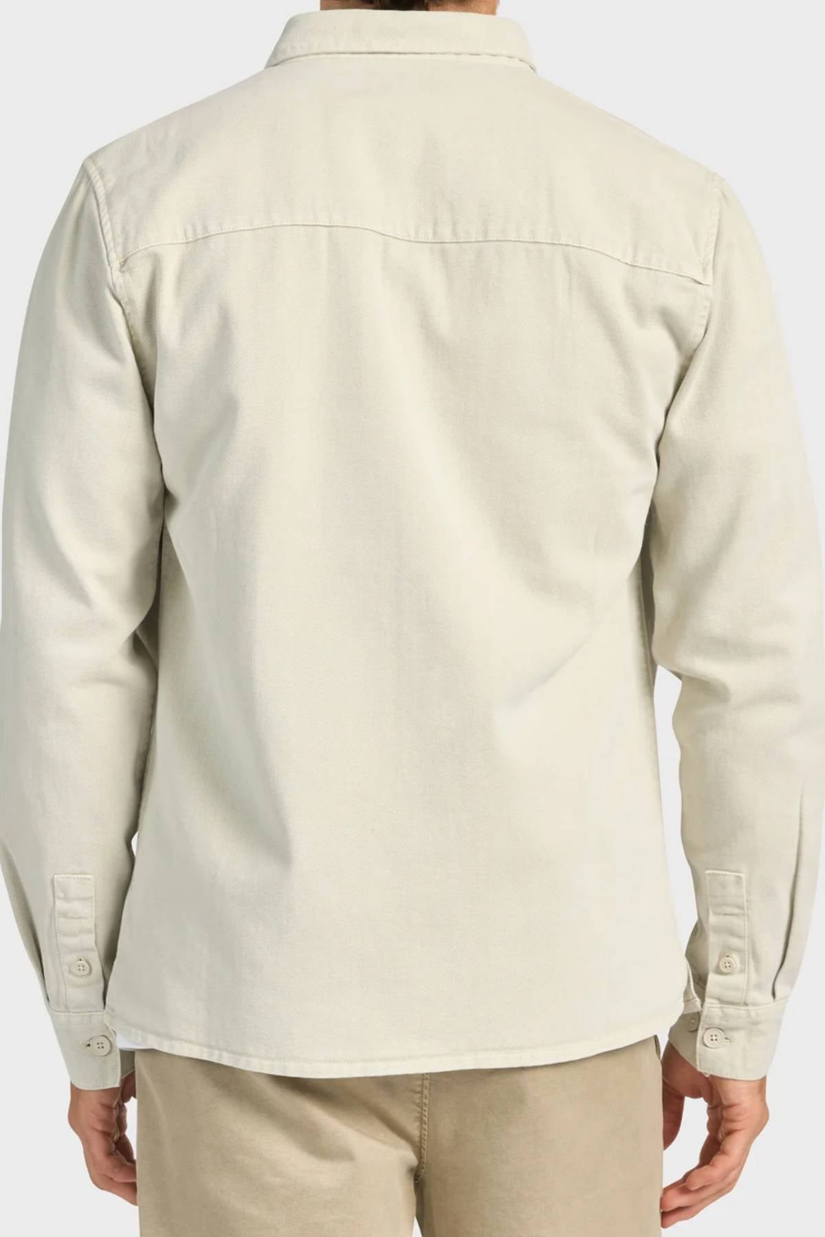 A person is shown from the back wearing the Academy Brand Essential Overshirt in light beige cotton twill with a collar and buttoned cuffs, paired with matching beige pants.