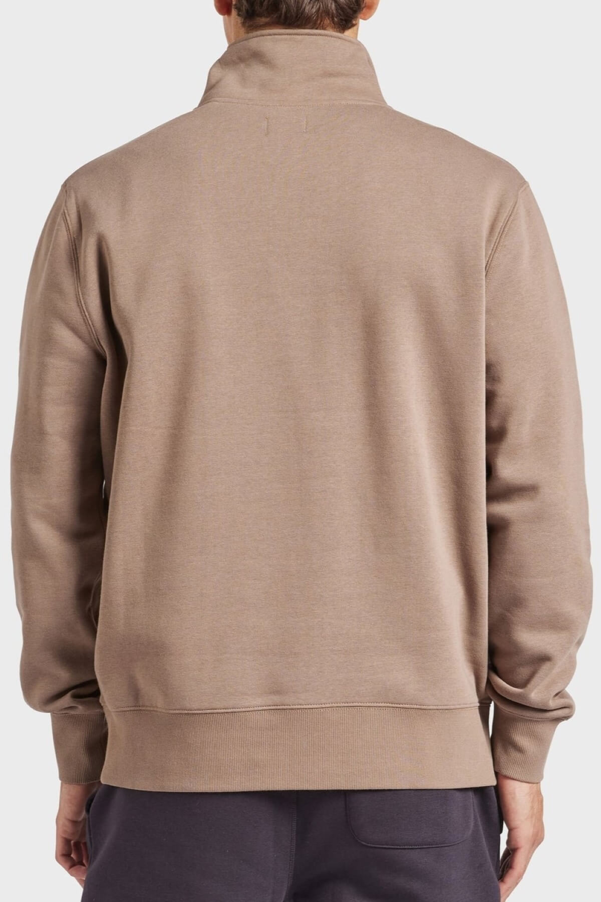 A person is seen from the back wearing an Academy Brand 1/2 Zip Sweat in taupe with a high collar. Made of premium brushed fleece, it features a relaxed fit and is paired with dark pants against a plain white background.