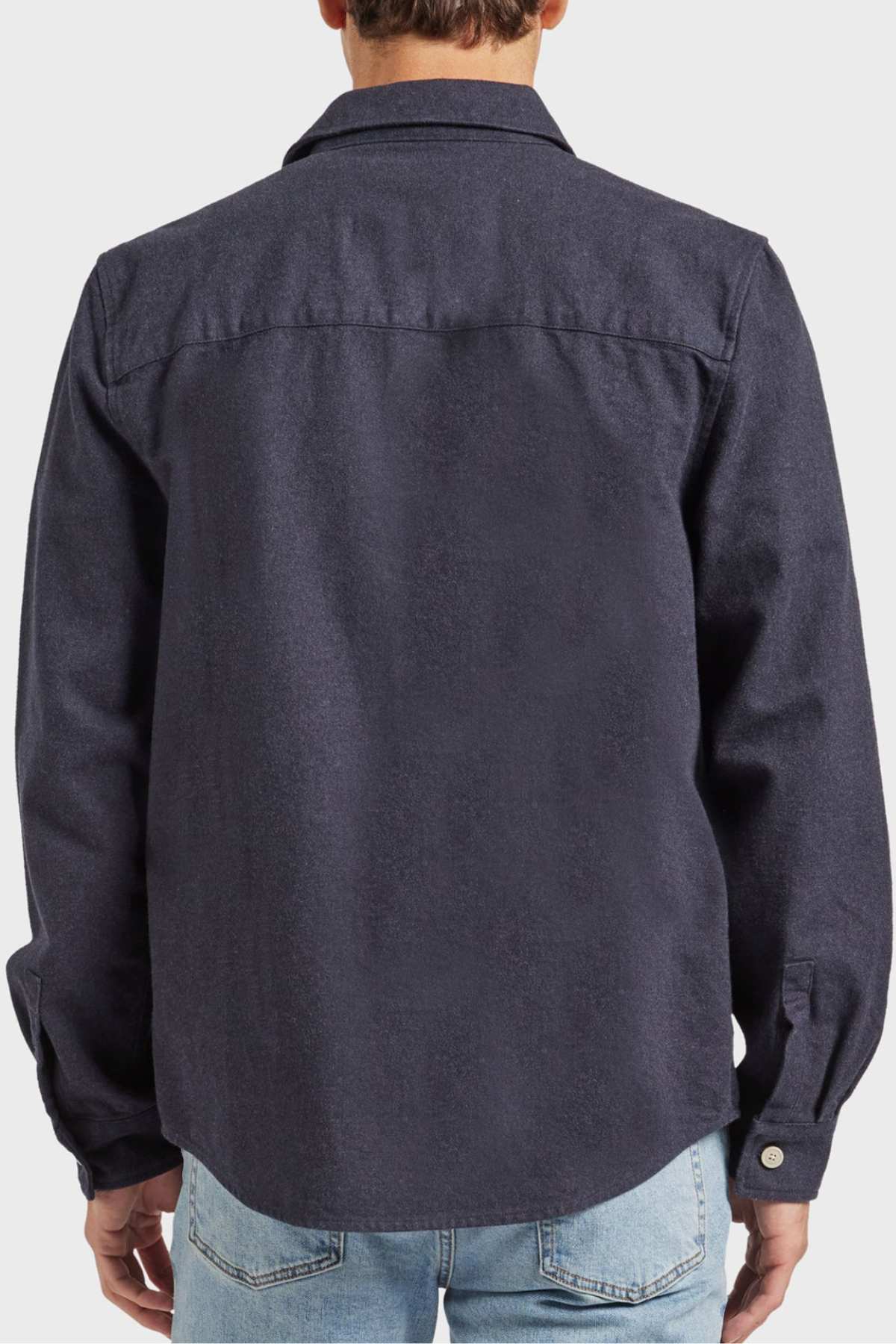A person wearing the Academy Brand Oakland Overshirt, crafted from premium yarn dye twill with a straight collar and medium-weight fabric, seen from the back. They are also dressed in light blue jeans.