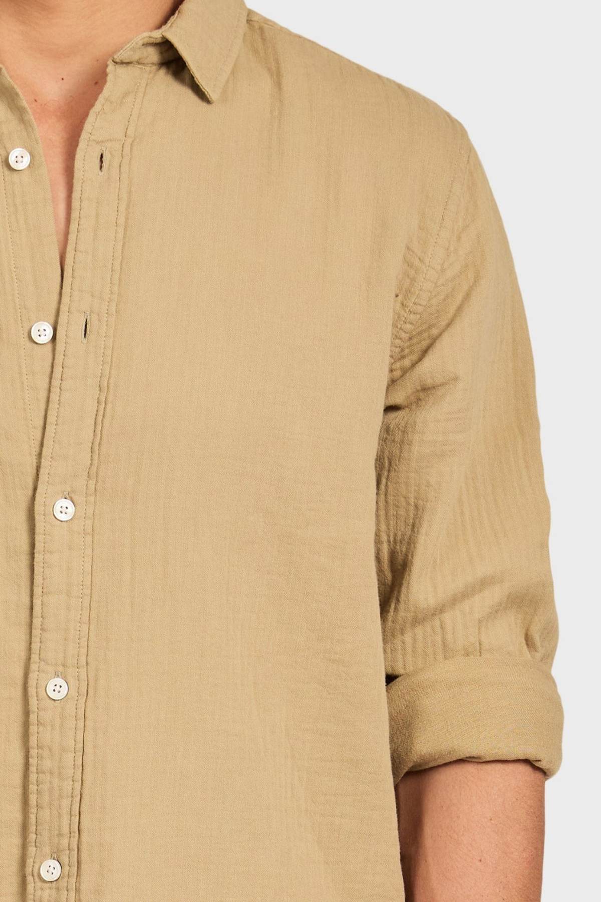 A person wearing a light brown Academy Brand Harry Double Cloth Shirt, a men's casual cotton shirt with a textured finish, left sleeve rolled up and partially unbuttoned, shown from shoulders to waist on a plain background.