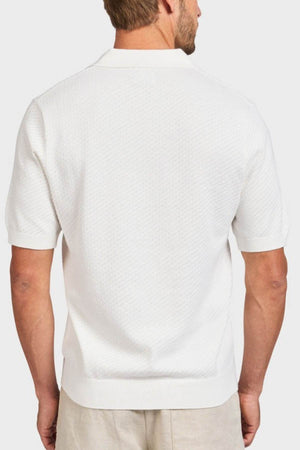 A man is shown from behind wearing the Academy Brand Jonny Textured Knit Polo in soft textured cotton with a subtle pattern, ribbed cuffs and waistband, paired with light pants against a plain white background.