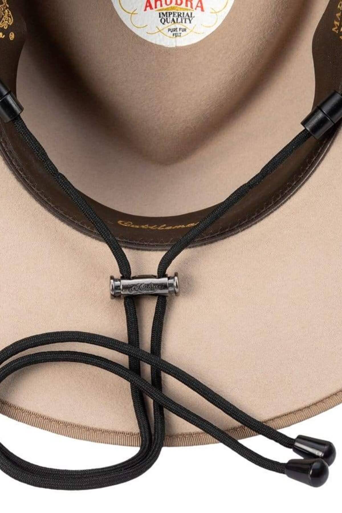 Close-up of the inside of a beige hat featuring a leather hatband and an Akubra Chinstrap with black cords. The label inside the hat reads "Imperial Quality," and part of the brand name "Andora" is visible.