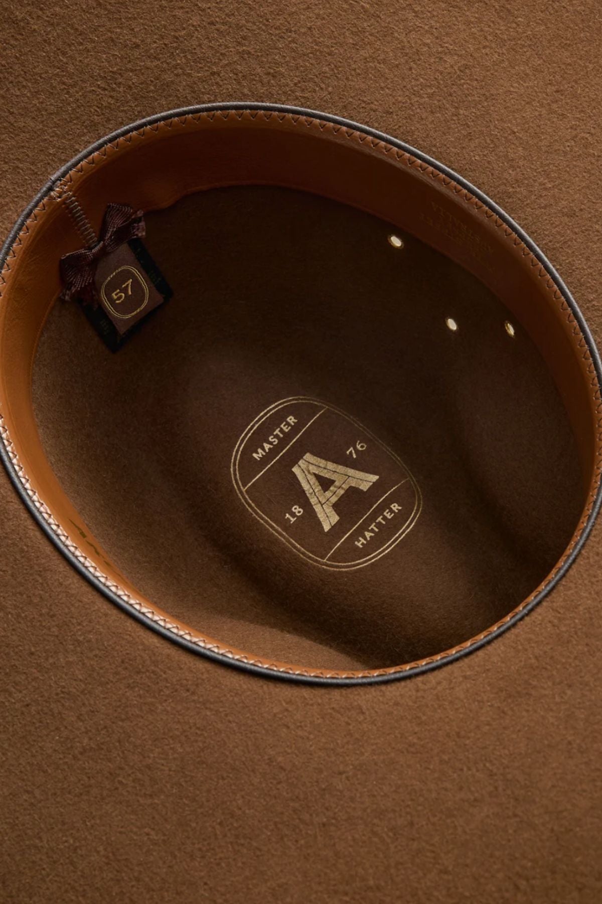 A close-up of the Akubra Riverina hat interior displays its leather sweatband, size 57 label, and gold "MASTER HATTER 1876" emblem—hallmarks of this classic Australian broad-brim farming hat renowned for sun protection.